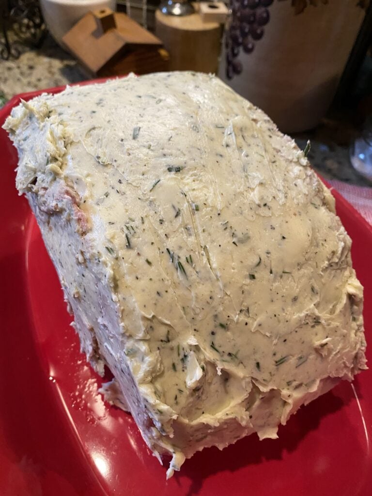 Seasoned bone-in rib roast covered in seasoned butter