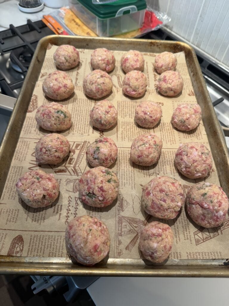 The meatballs on a baking sheet before cooking