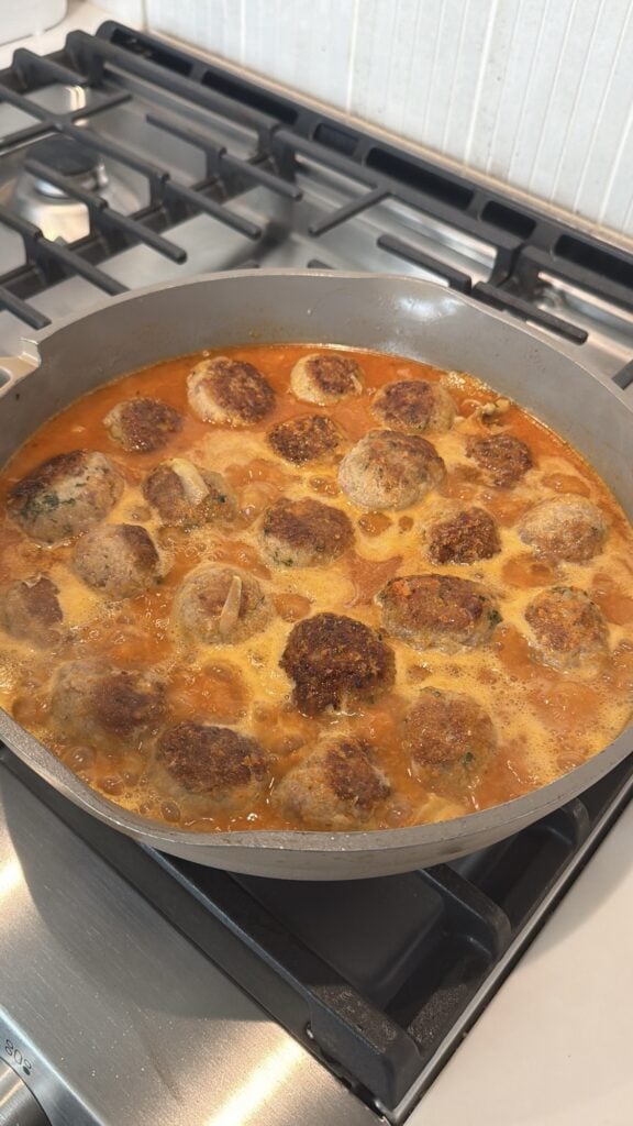 Meatballs simmering in the sauce