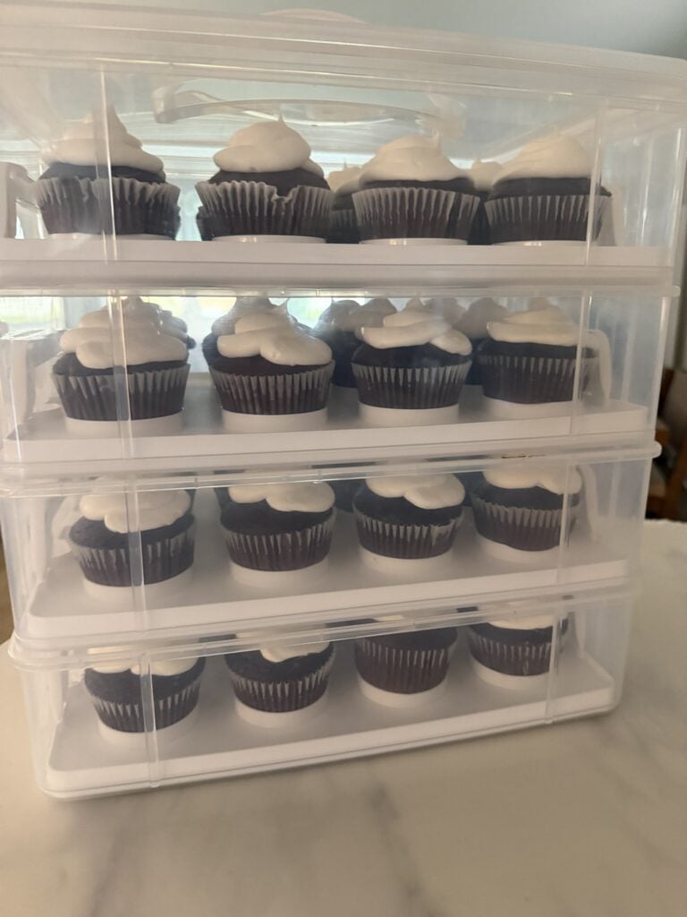Stackable cupcake carriers filled with frosted chocolate cupcakes prepared ahead for a party