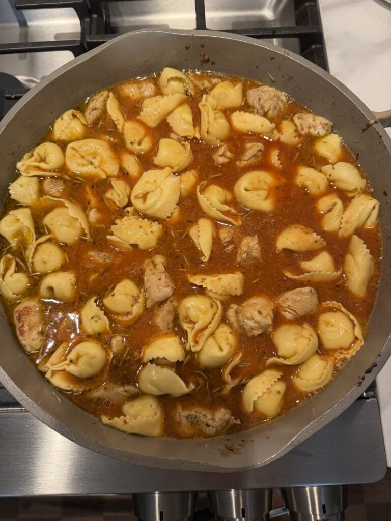 Fresh cheese tortellini and chicken in sauce in the pan