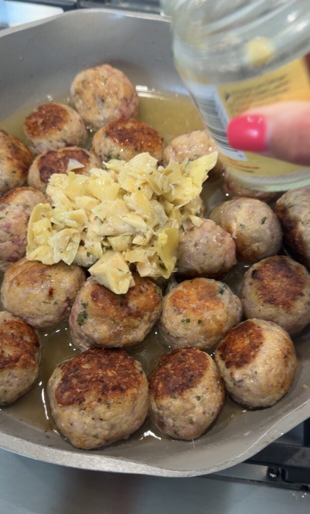 Artichoke pieces over the cooking meatballs