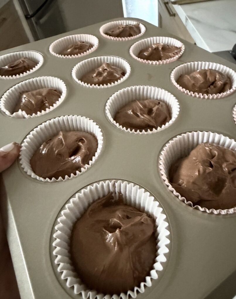 Chocolate cupcake batter filling paper cupcake liners three quarters full before baking