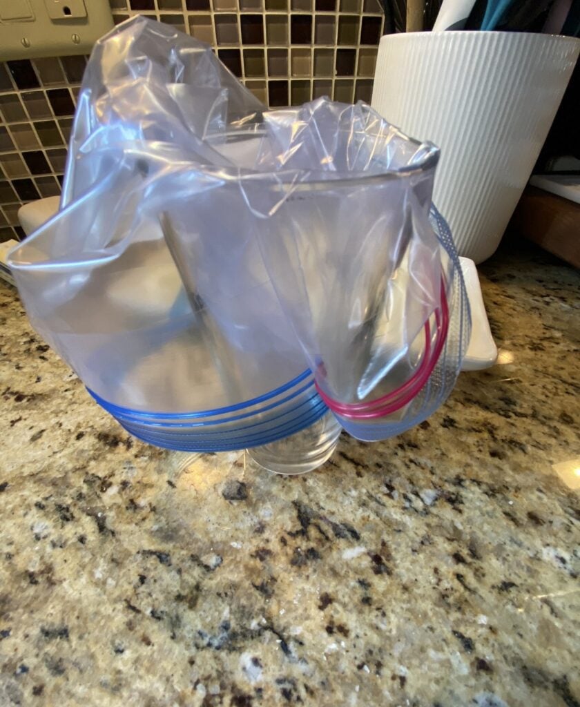 Disposable pastry bag held open inside and over a pint glass for easy filling with frosting
