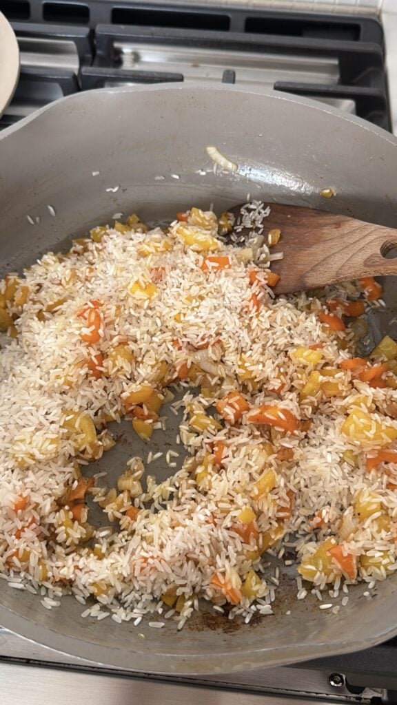 Sautéed vegetables and rice browning in skillet