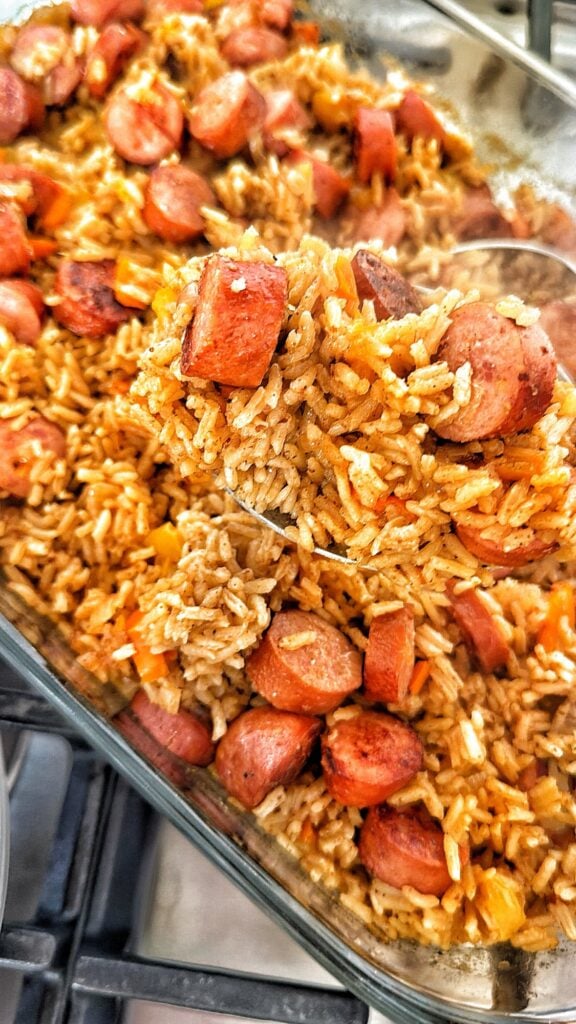 Cheddar brat and rice bake with sliced cheddar bratwurst, peppers and seasoned rice in a casserole dish.
