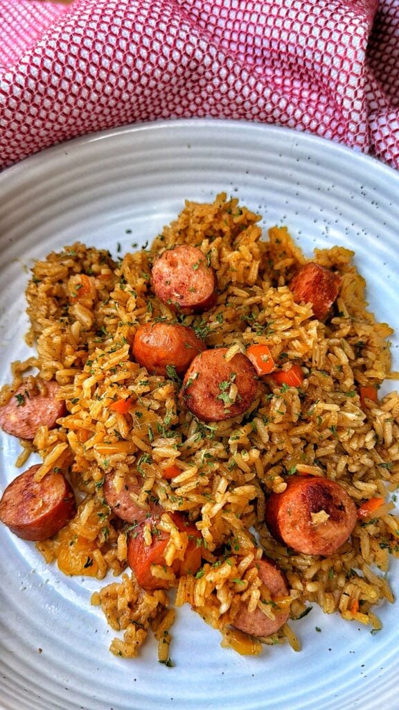Serving of cheddar brat and rice bake with tender seasoned rice, sausage, peppers and onions.