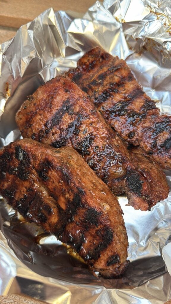 Grilled sirloin steaks resting under foil before slicing to keep them juicy and tender.
