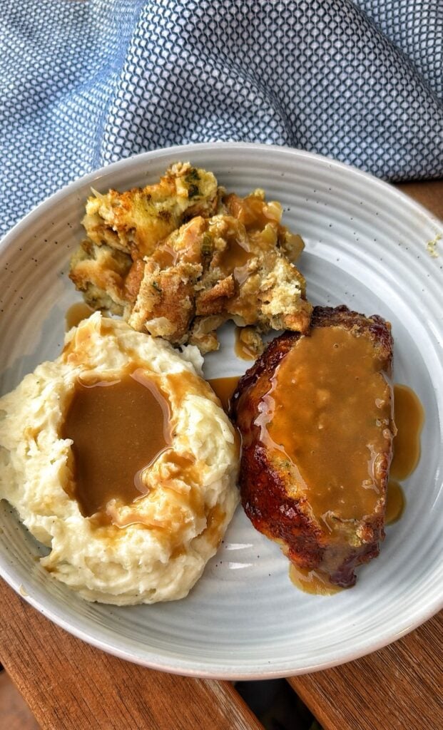 Individual Thanksgiving turkey meatloaf meal with mashed potatoes, gravy, cranberry sauce, and stuffing.