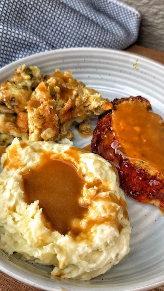 Thanksgiving turkey meatloaf made with ground turkey and stuffing served with mashed potatoes, gravy, and cranberry sauce.