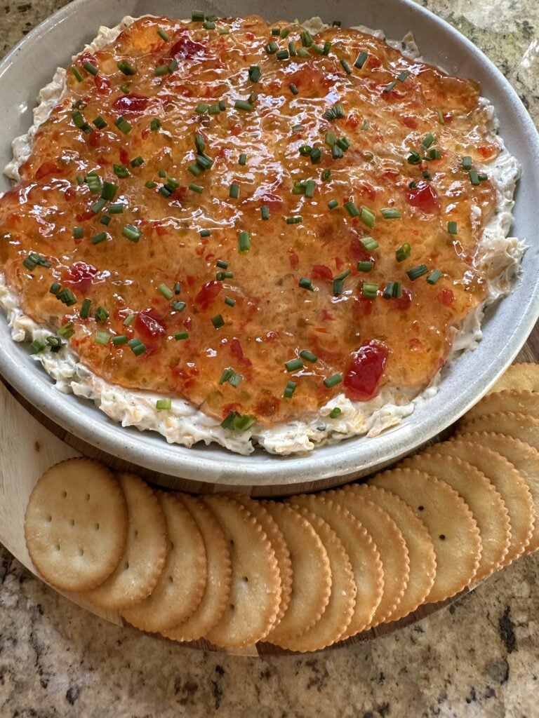 Pepper Jelly Cheese Dip made with cream cheese, cheddar, pepper jack, sweet pepper jelly and fresh chives served with buttery crackers.