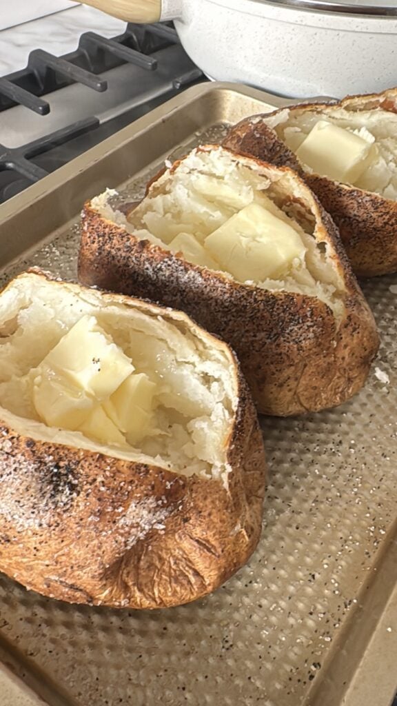 Crispy baked russet potatoes split open and topped with butter