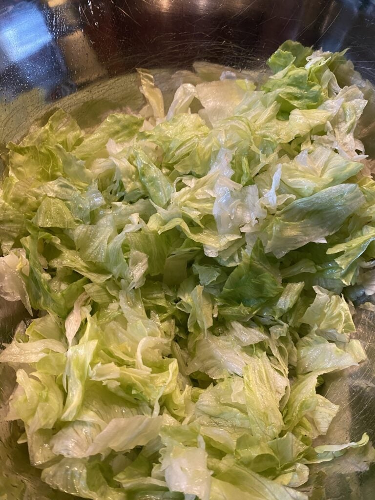Chopped iceberg lettuce in a large bowl for Midwestern Taco Salad