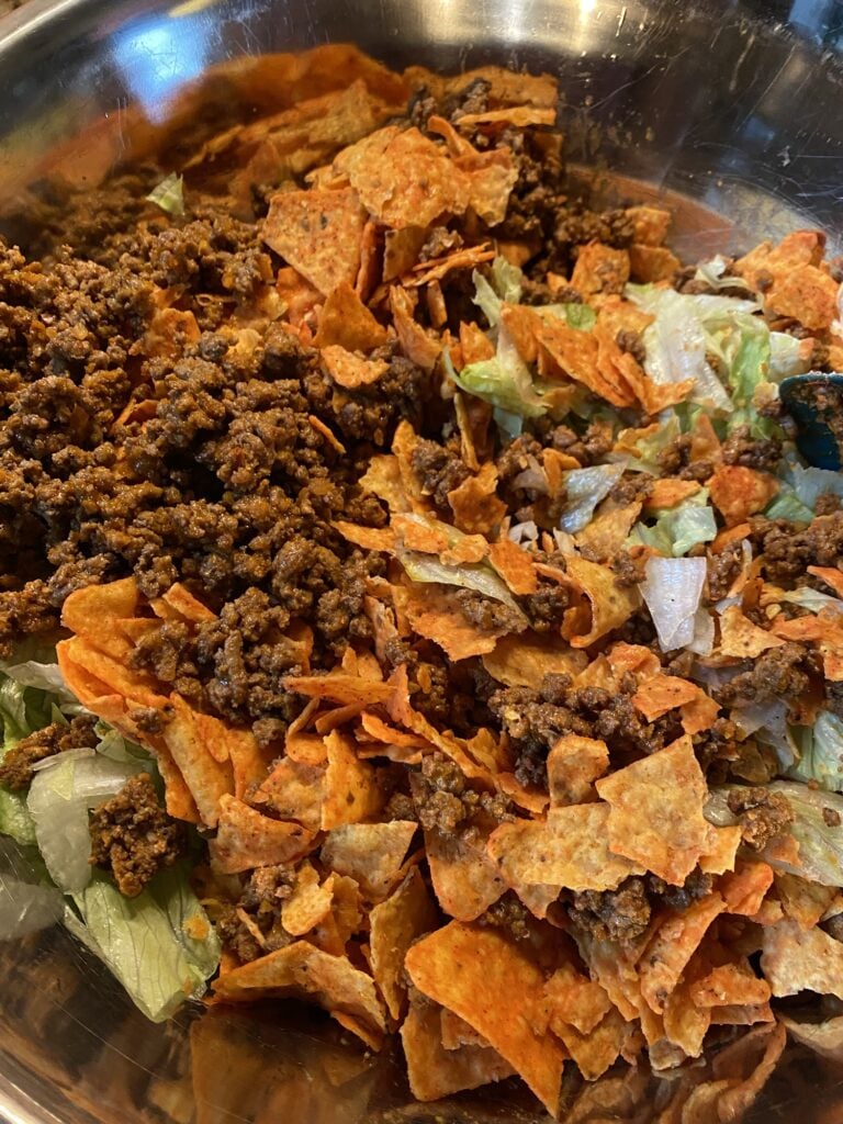 Large bowl of Midwestern Taco Salad with iceberg lettuce, Doritos, ground beef, and shredded cheese
