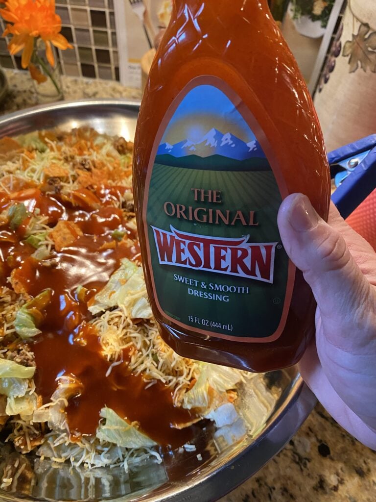Western Dressing poured over Midwestern Taco Salad with Doritos, beef, cheese, and iceberg lettuce