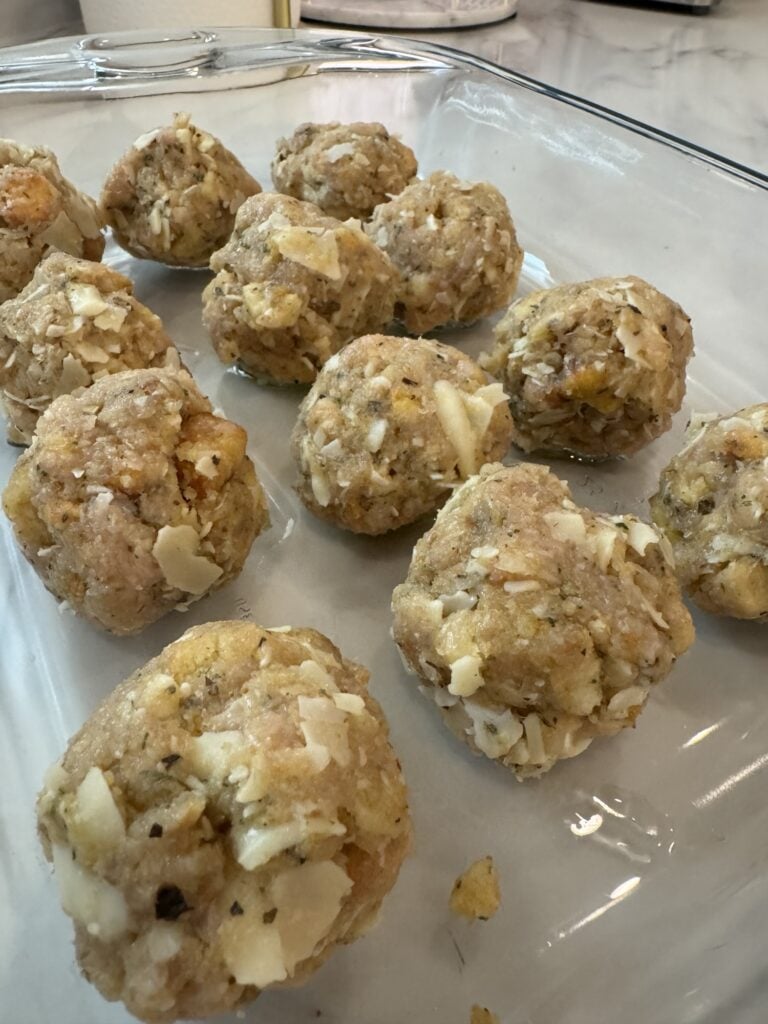 Raw Chicken Parmesan Meatballs resting in an oiled baking dish before baking