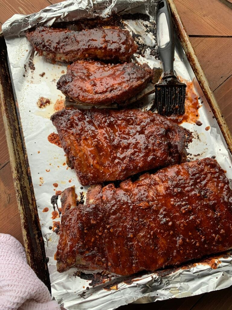 Pork ribs being basted with barbecue sauce 