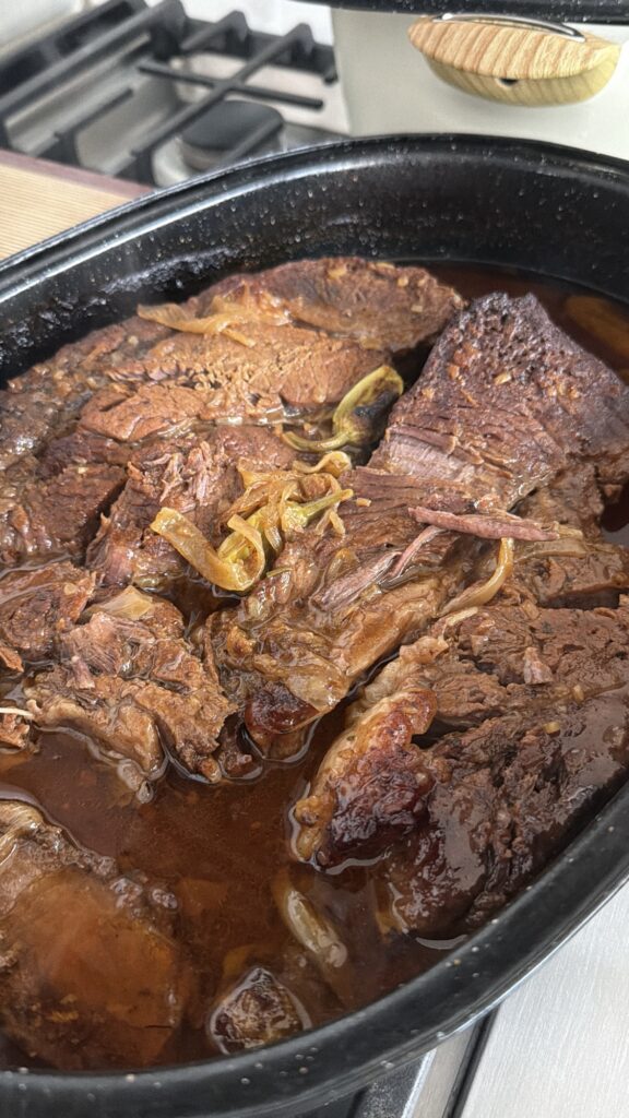 Fork tender shredded Steakhouse Onion Pot Roast soaking in rich onion gravy