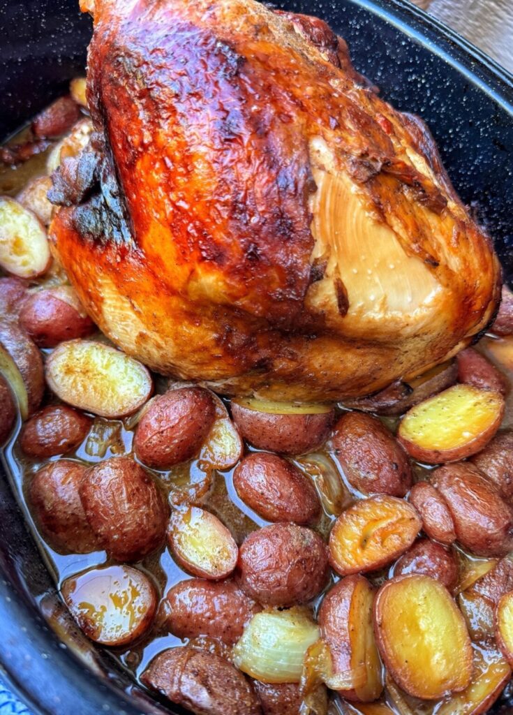 a turkey breast with roasted potatoes in a speckled roaster