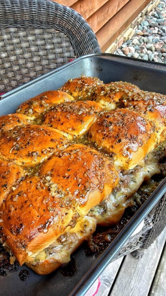 slider sandwiches layered with ham and cheese in a pan
