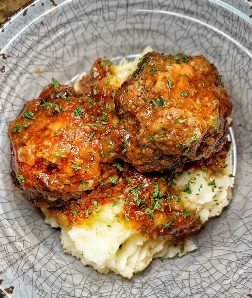 meatballs served on mashed potatoes with a tomato gravy