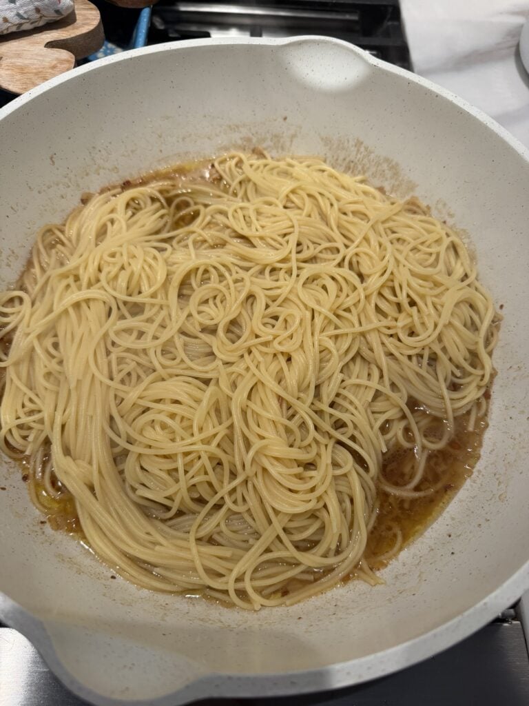 Spaghetti being tossed in silky Worcestershire butter and Parmesan sauce