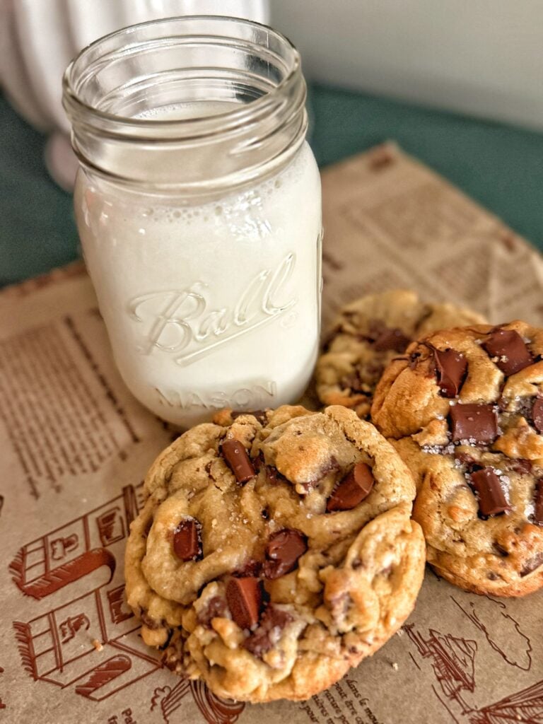 Ultimate jumbo chocolate chip cookies with chocolate chunks and flaky sea salt next to a glass of milk