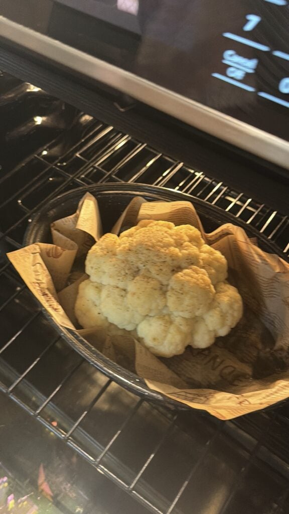 Whole cauliflower after steaming in a roasting pan before browning.