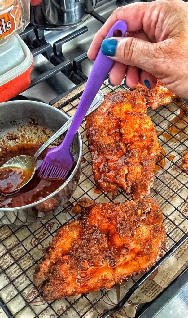 Brushing spicy Chicago hot chicken butter sauce over freshly fried crispy chicken