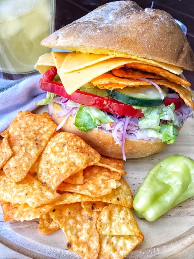 ham and cheese sandwich on a roll with lettuce, onions, tomato and pepper, served with Doritos chips