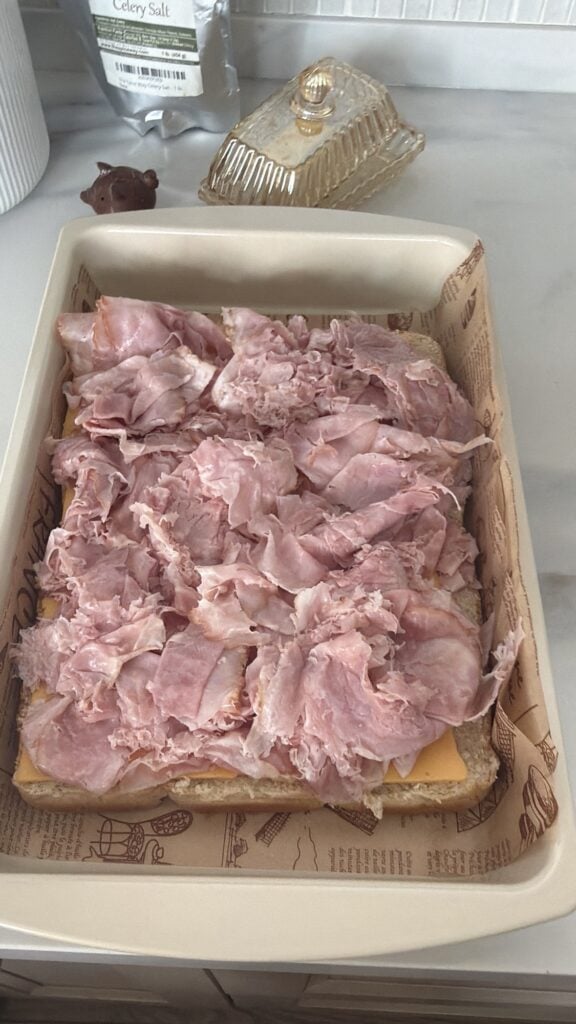 Shaved ham on top of cheese on slider bun bottoms