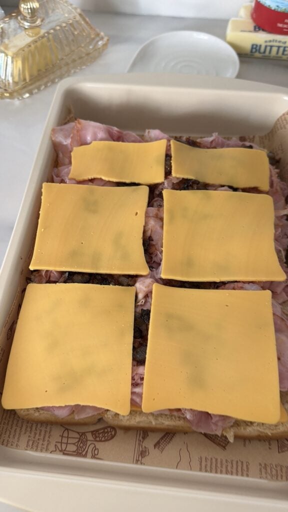 Another layer of cheese applied to the sliders before baking