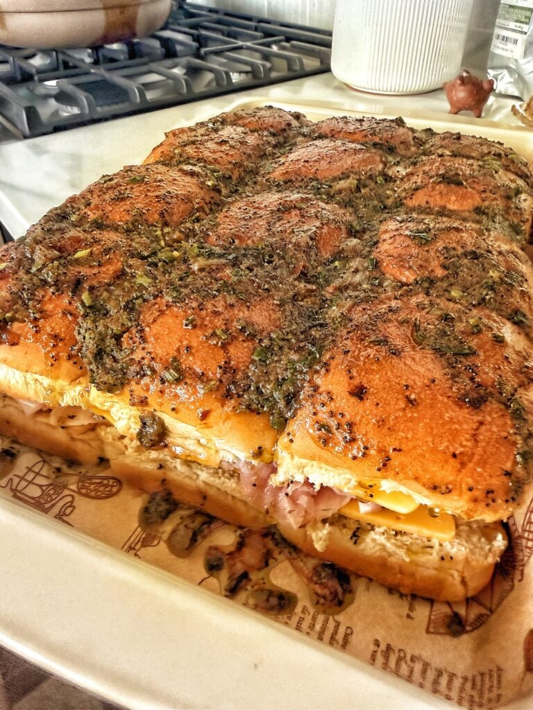 Ham and cheese sliders topped with homemade caramelized onion butter before baking.