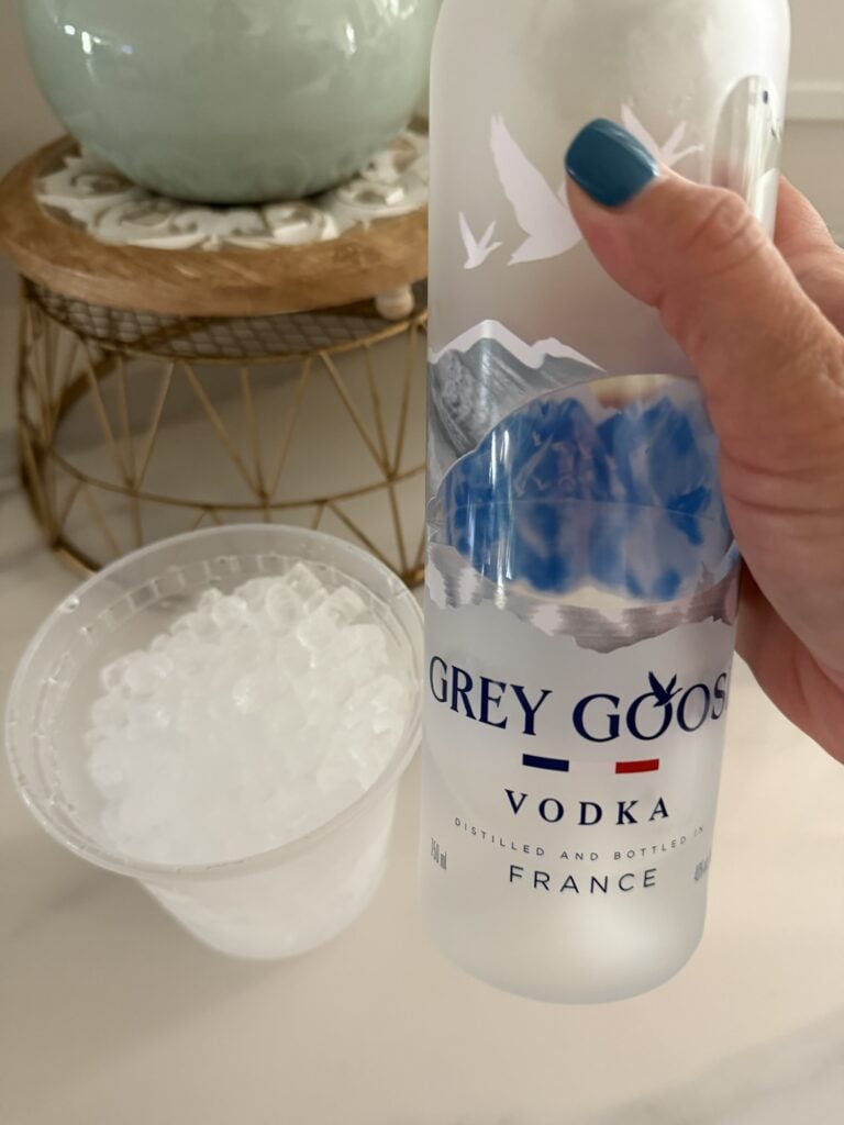 Bottle of grey goose vodka and a cup of ice to make the cocktail in