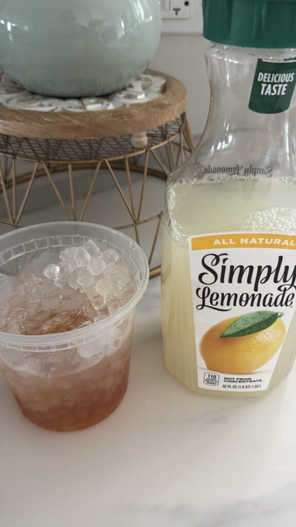The alcohols in a cup next to a bottle of lemonade