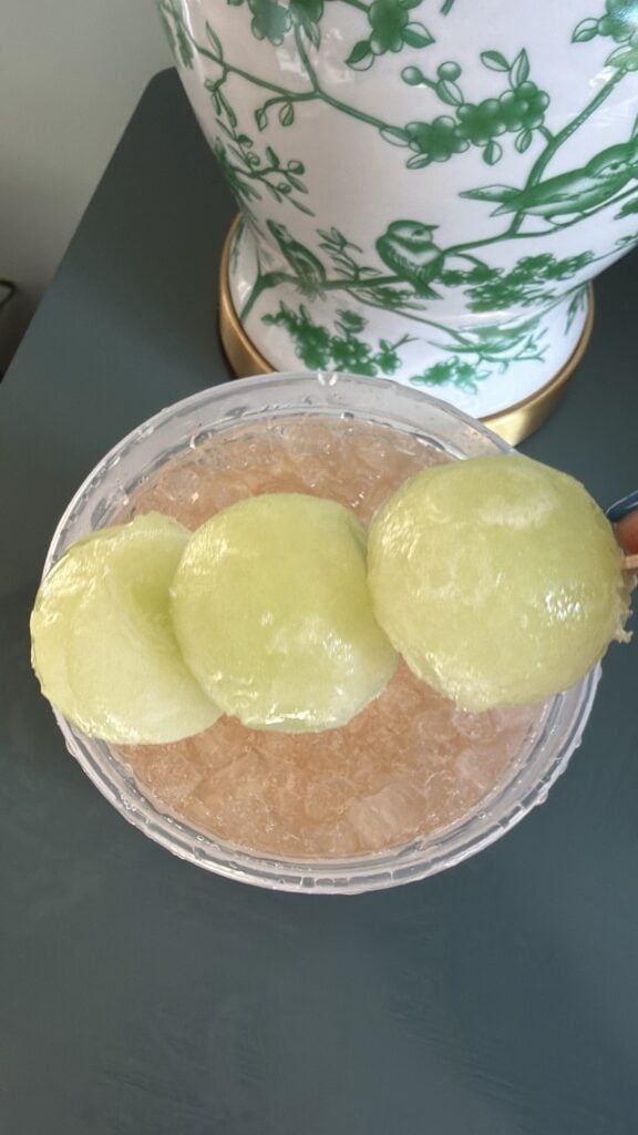 Frozen honeydew melon tennis ball garnish in a Honey Deuce vodka lemonade cocktail