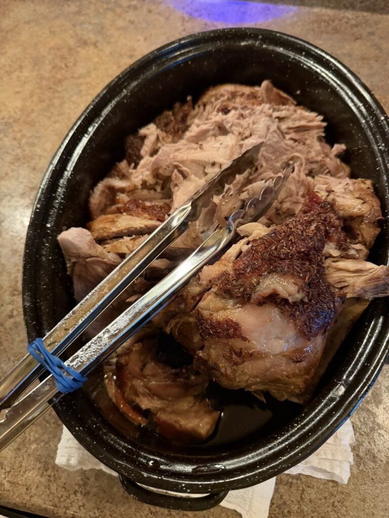 Tender slow-roasted pork shoulder pulling apart easily after several hours in the oven.