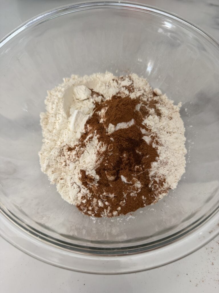 a bowl of the dry ingredients with the unique spices of clove and nutmeg on top