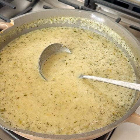 a skillet o creamy celery soup with a ladle in it