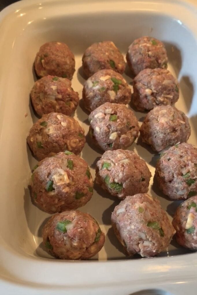 Raw meatloaf meatballs arranged closely together in a 9x13 baking dish
