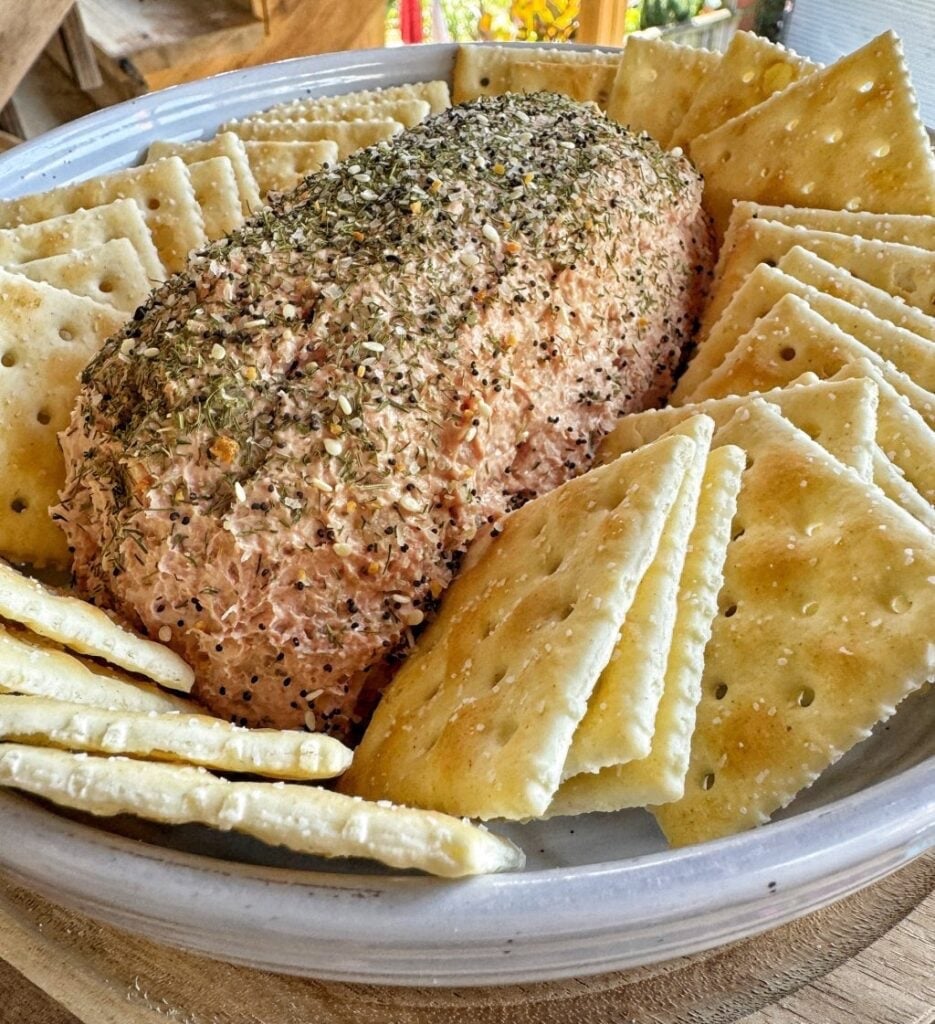 Loaf of liver sausage spread topped with dill and seasoning and surrounded by saltine crackers