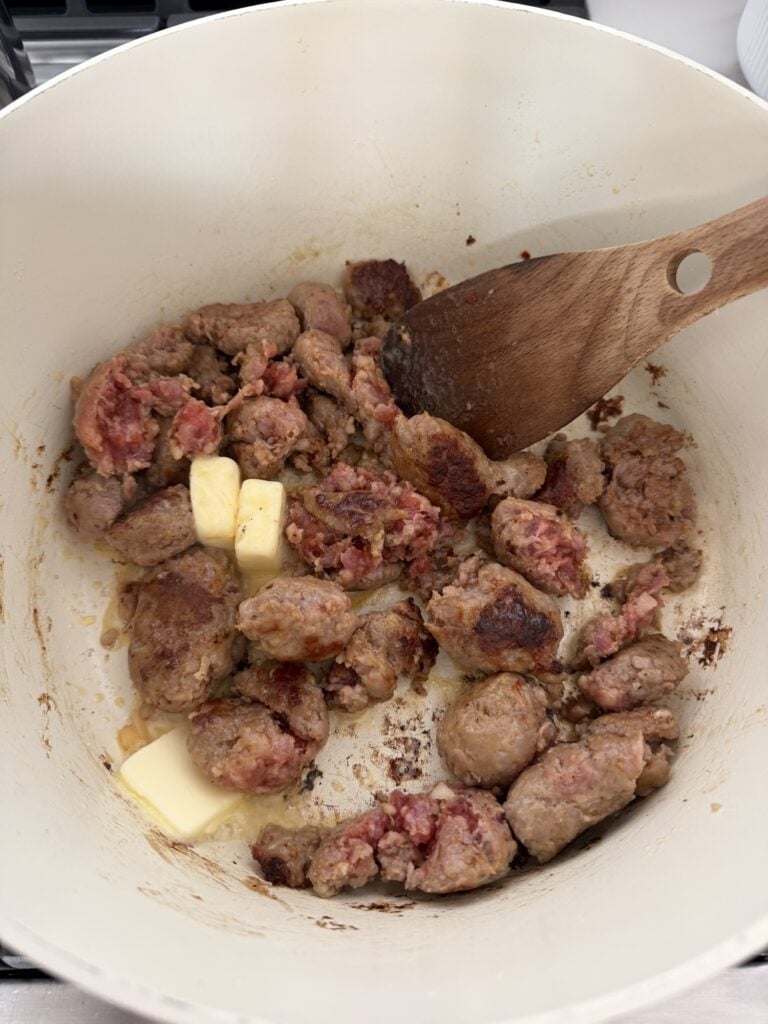 Italian sausage and diced onion browning in a soup pot for pumpkin tortellini soup.