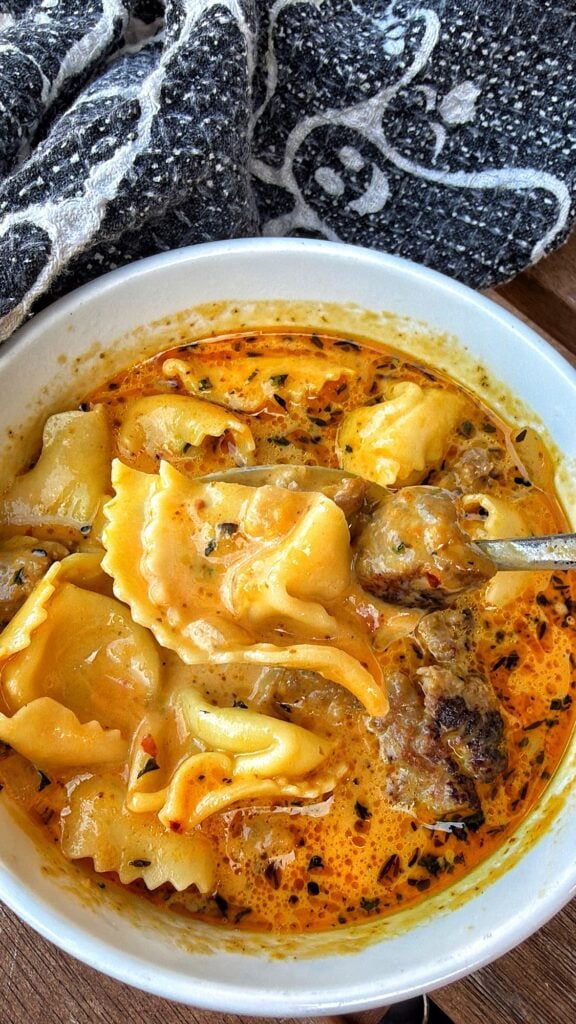 Harvest Moon pumpkin sausage tortellini soup with Italian sausage, spinach, Parmesan, and cheese tortellini in a creamy pumpkin broth.