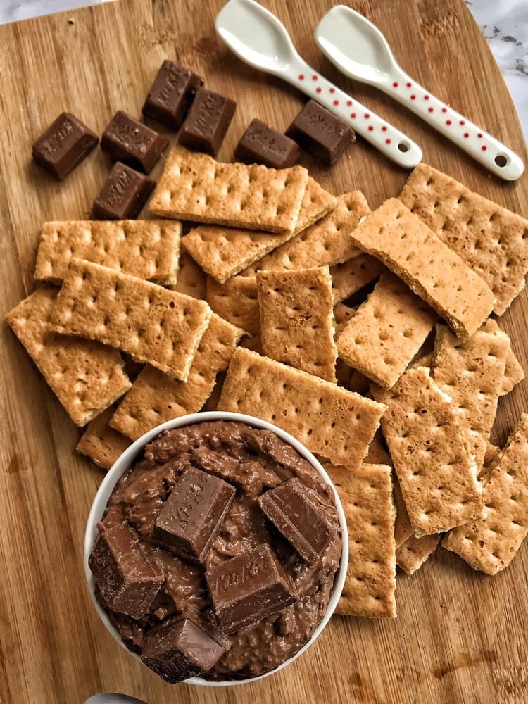 a cup of chocolate kit kat dip with graham crackers and chocolate chunks