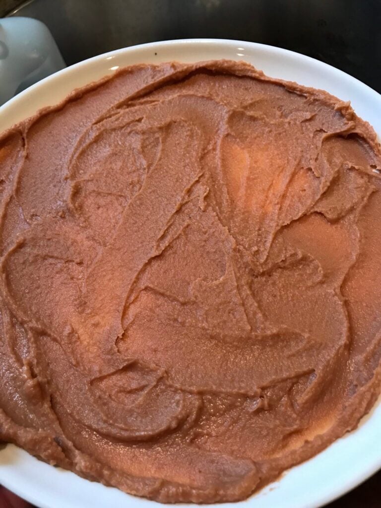Smooth bean dip spread on a plate for layered Halloween Taco Dip