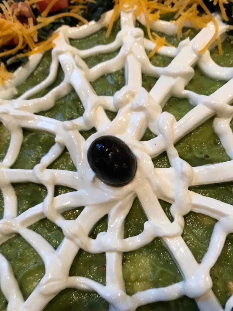 a black olive in the center of the sour cream spiderweb