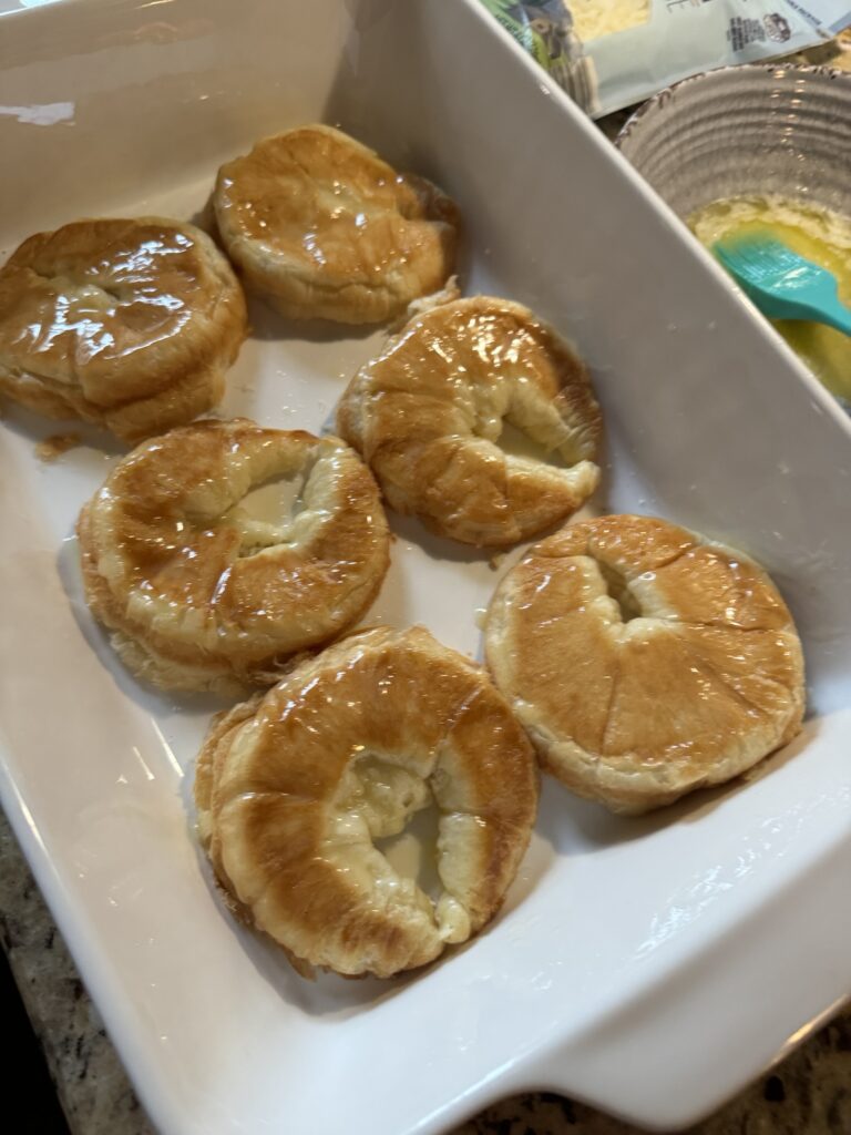 Butter croissants sliced open and arranged in a baking dish for make-ahead ham and cheese croissants.