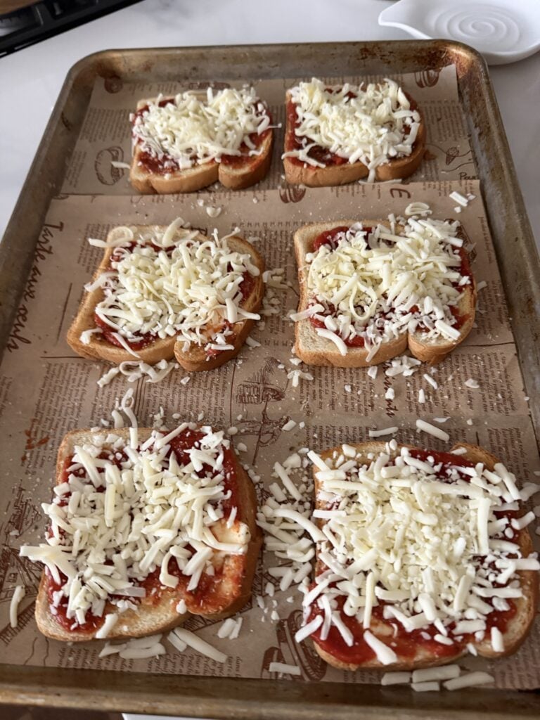 Toasted white bread spread with butter, garlic salt, and pizza sauce.