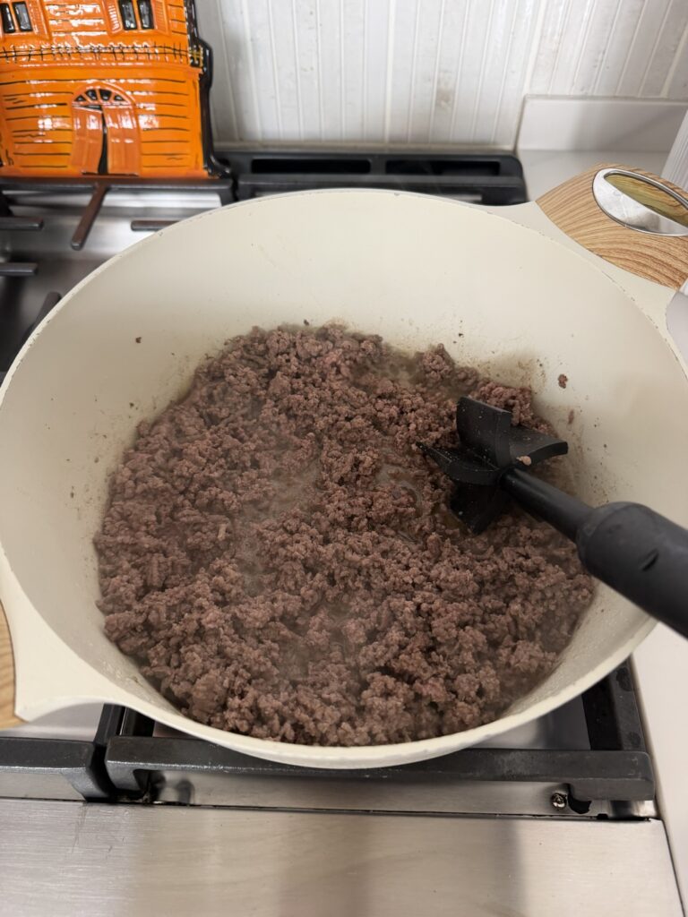 Ground beef browned and broken into a fine crumble in a pot.