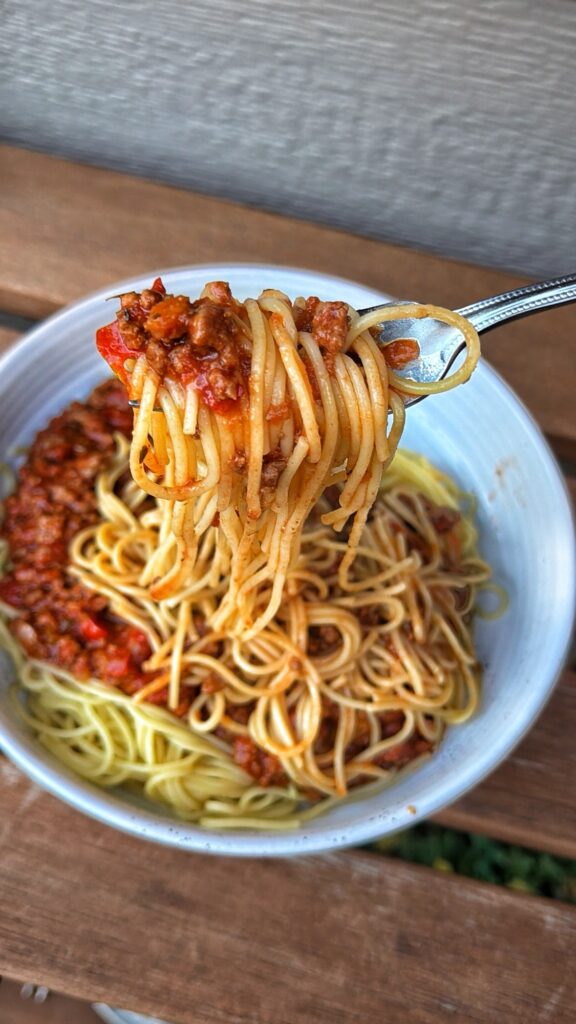 bowl of chicago style meat sauce with spaghetti with a fork full of pasta and meat sauce
